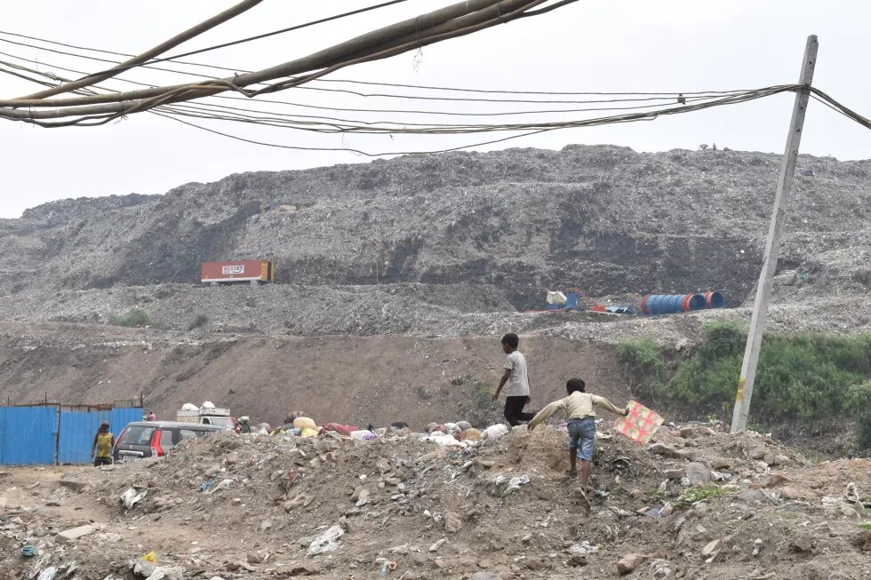 A boy running with his kite towards the Ghazipur landfill to say hello to his neighbour working on the dump.